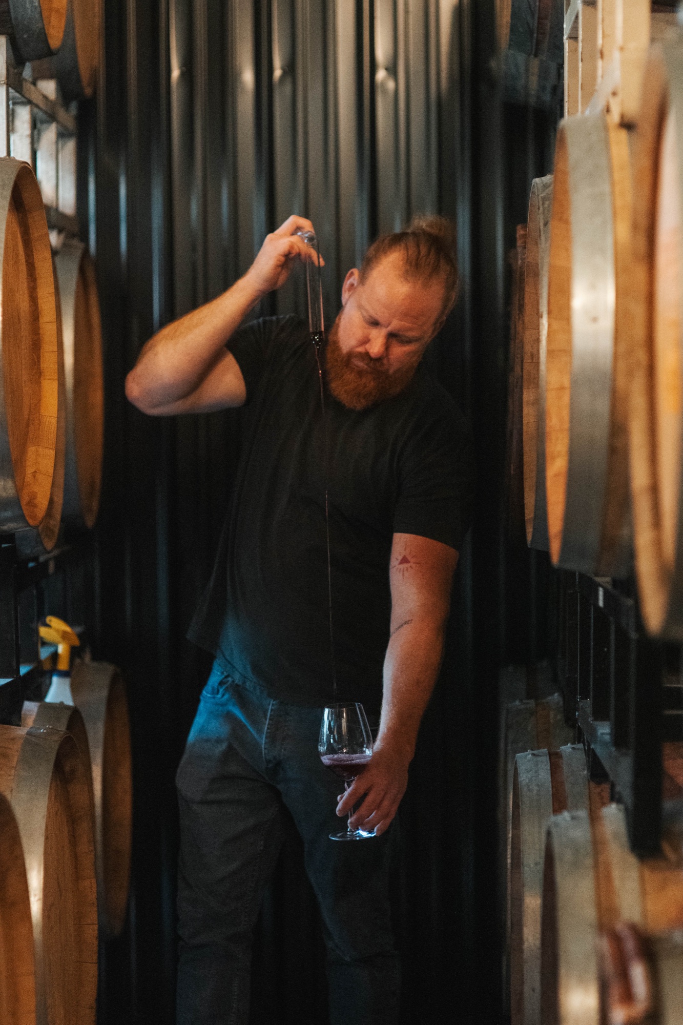 A Cellar Beast winemaker drawing a barrel sample with a wine thief