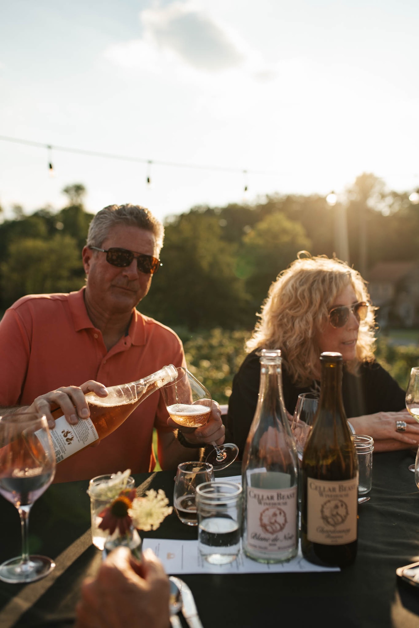 A guest pouring Cellar Beast Blanc de Noir at a vineyard dinner